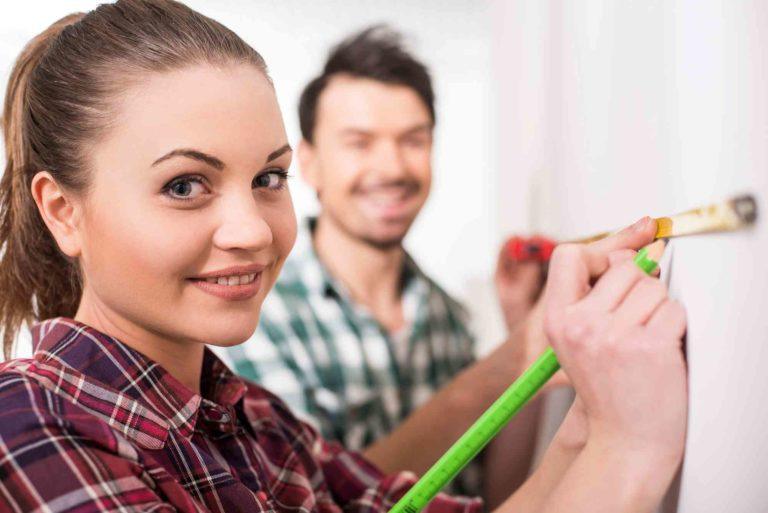 Ein Paar messt an der Wand den Abstand